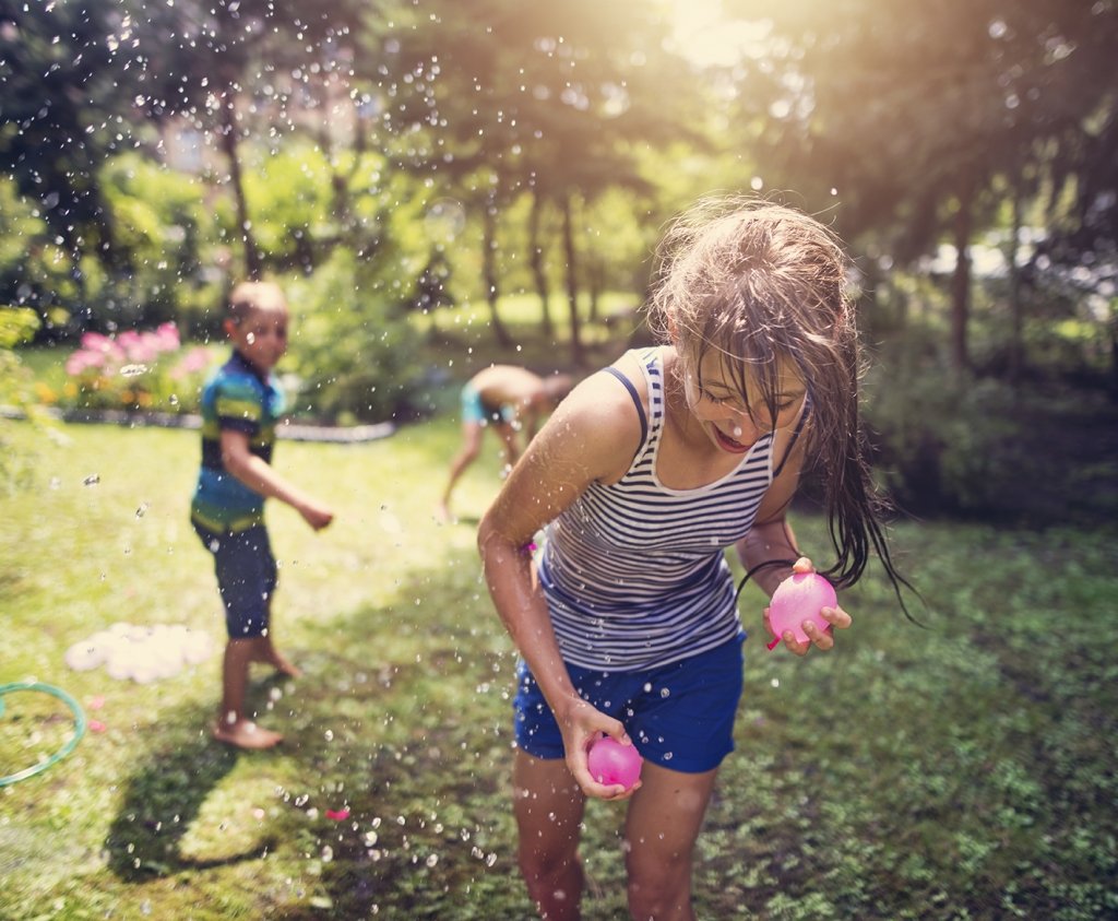 children playing with water balloons in their back yard